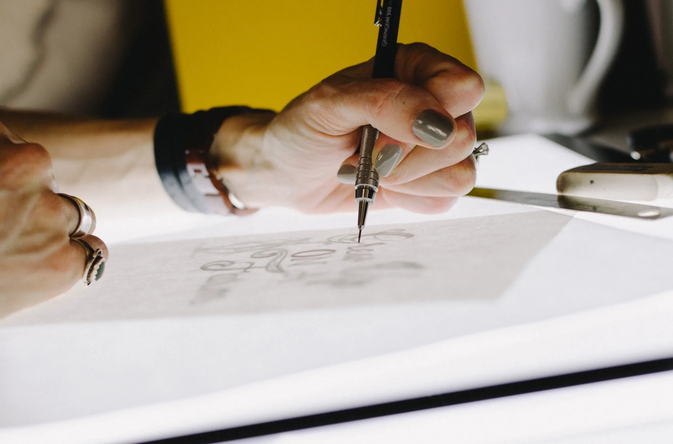 Designer dessinant un logo sur une table lumineuse
